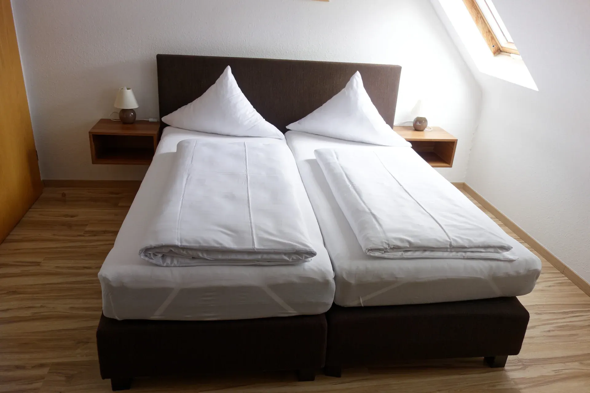 Doppelzimmer mit heller Bettwäsche und Holzmobiliar