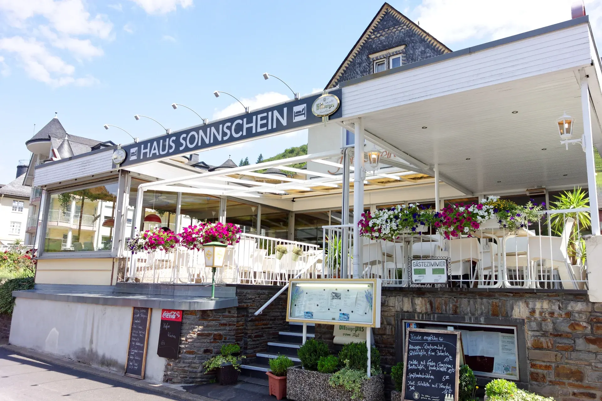 Front des Hauses Sonn’schein mit Balkonen und Restaurantterrasse