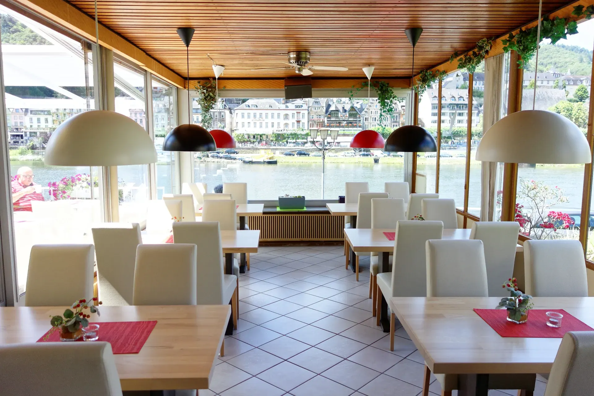 Restaurant mit gedeckten Tischen und breiter Fensterfront